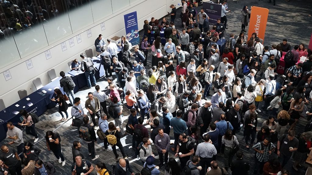 Overhead image of a large crowd of people walking throughout a convention center floor.