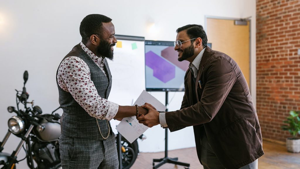 A black and an Asian man shaking hands in an office
